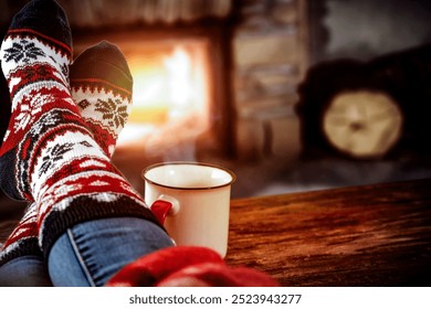 Legs in warm socks and a mug with hot drink. Person drinking tea at the fireplace in cozy home interior. - Powered by Shutterstock