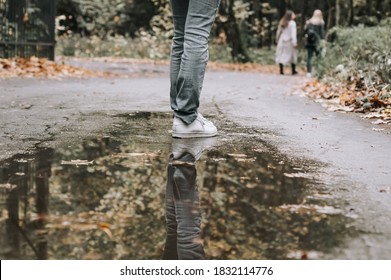 legs in white sneakers reflected in a puddle. Reflection of girl wearing white shoes in water puddle - Powered by Shutterstock