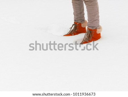 Legs in winter boots with fur in the snow