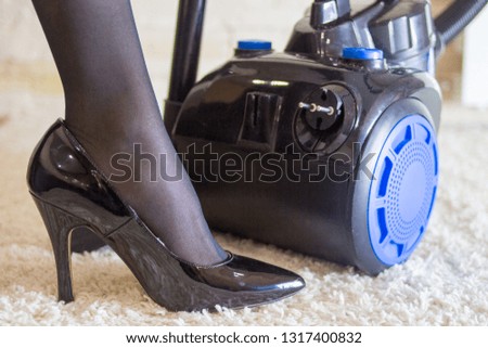 legs of a woman in black shoes near the vacuum cleaner