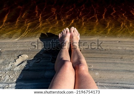 Legs of a woman by the river against reddish water in the background. Guaibim beach in the city of Valenca, Bahia, Brazil.