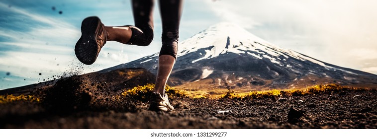 Legs of the woman running on the trail with volcano on the background