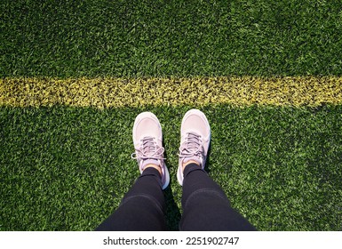 Legs of a woman standing on a green sports playground in front of a yellow line, top view - Shutterstock ID 2251902747