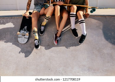 Legs of women sitting on ramp at skate park. Cropped shot of female skaters resting on ramp after skateboarding. - Powered by Shutterstock