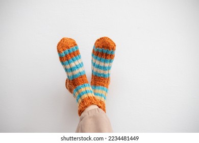 Legs in woolen socks on a white background. Warm socks for winter cold. Handmade knitting.