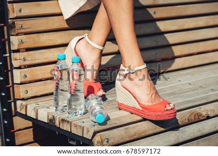 legs of a Young girl with a bottles of water on a bench