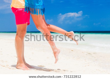 legs of young hugging couple on tropical turquoise beach