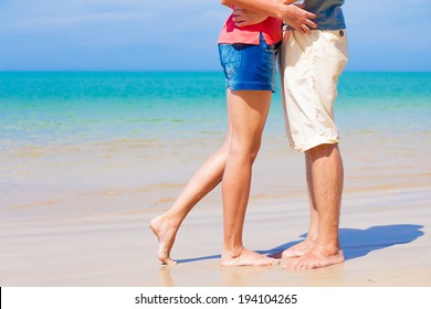 legs of young kissing couple on tropical turquoise Thailand beach
