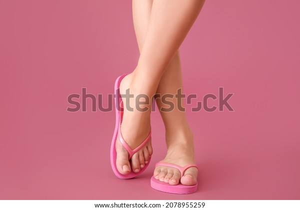 Legs of\
young woman in flip-flops on color\
background