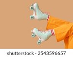 Legs of young woman in roller skates on brown background