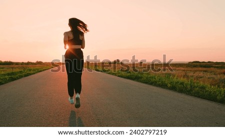 Legs of young woman run along asphalt at sunset in summer. Running after sun. Training jogging. Jogging outside city, Beautiful girl doing fitness, jogging on road in sun. Jogger girl breathes outdoor
