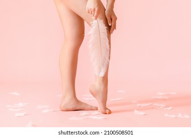 Legs Of Young Woman With Soft Feather On Color Background. Epilation Concept