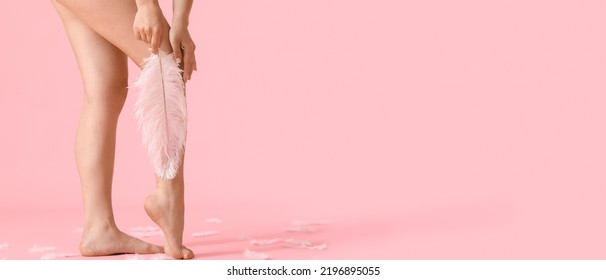 Legs Of Young Woman With Soft Feather On Pink Background With Space For Text. Epilation Concept