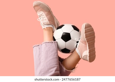 Legs of young woman in stylish sneakers with soccer ball on pink background - Powered by Shutterstock