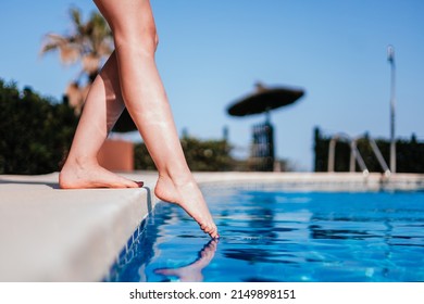 Legs Of Young Woman Testing Water Temperature In A Resort