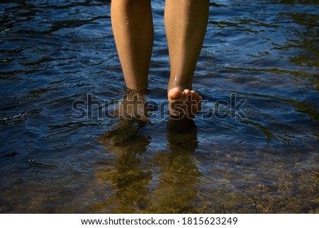 Legs of a young woman walking by the sea.
Young woman's barefoot walking in the stream. Front view.