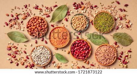 Legumes assortment, overhead panoramic shot on a brown background. Lentils, soybeans, chickpeas, red kidney beans, black-eyed peas, a vatiety of pulses