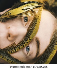 Lehi, UT / Male Blue Eyed Model Laying Down With Yellow Feathers On Face