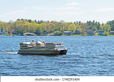 Leicester, Massachusetts/USA - May 22 2020: A Couple Enjoy A Leisurely Cruise With Their Pontoon Boat On Cedar Meadows Pond In Central Massachusetts.