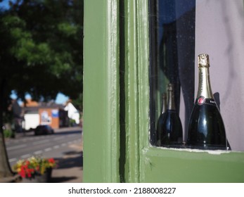 Leicester,United Kingdom - 08,07,2022: A Bottle Of Fizzy Wine In The Window Of A Public House With The Street And Path In Blurred Focus.