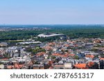 Leipzig cityscape with rooftops and stadium surrounded by trees under a clear sky