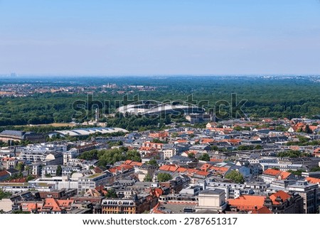 Leipzig cityscape with rooftops and stadium surrounded by trees under a clear sky