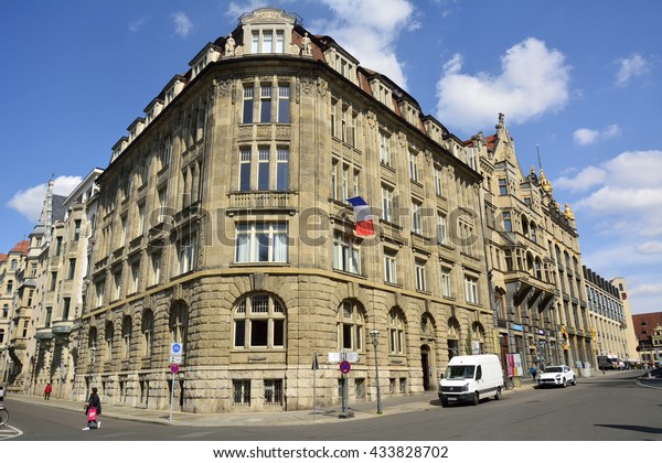 LEIPZIG, GERMANY - APRIL 8,\
2016. View of a historical building on the intersection of\
Thomaskirchhof and Dittrichring streets in Leipzig, with cars,\
taxis and people.