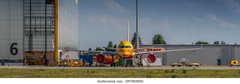 Leipzig Schkeuditz, Germany, June 2021 DHL cargo hub with DHL Boeing 757 cargo airplane parked in front of maintenance hangar - engines protected by red covers