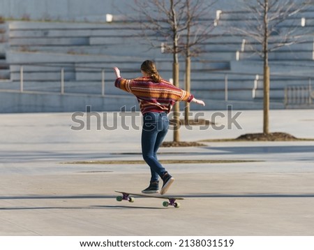 Leisure activity in spring day. Sportive lifestyle. Goofy. Young woman riding skateboard.  Closeup photography. Back, rear view