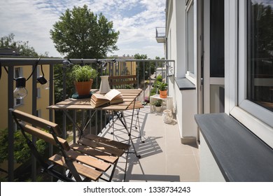 Leisure Area On A Balcony In A City Apartment With Wooden Table And Chairs