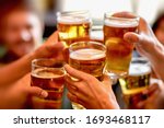 leisure, drinks, celebration, people and holidays concept - smiling friends drinking beer and stitching glasses in a restaurant or pub