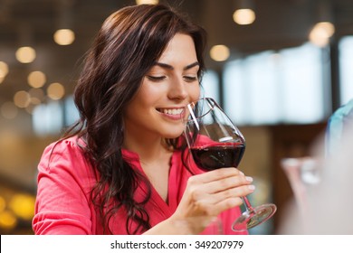 leisure, drinks, degustation, people and holidays concept - smiling woman drinking red wine at restaurant - Powered by Shutterstock