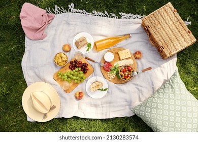 leisure and eating concept - close up of food, drinks and picnic basket on blanket on grass at summer park - Shutterstock ID 2130283574