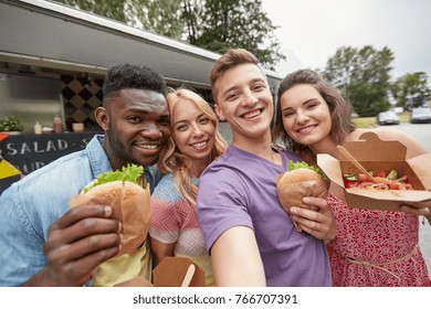 leisure, eating and people concept - happy friends with wok and burgers taking selfie at food truck - Powered by Shutterstock