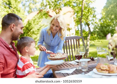 Leisure, Family And People Concept - Happy Mother, Father And Little Son Eating Pie At Festive Dinner Or Summer Garden Party