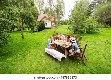 Leisure, Holidays, Eating, People And Food Concept - Happy Friends Having Dinner At Summer Garden Party