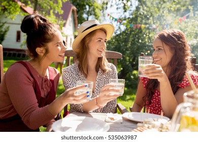 Leisure, Holidays, Eating, People And Food Concept - Happy Women Or Friends With Drinks Celebrating Reunion And Having Dinner At Summer Garden Party