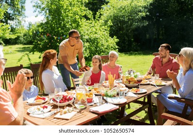 leisure, holidays and people concept - happy family having festive dinner or barbecue party at summer garden - Powered by Shutterstock