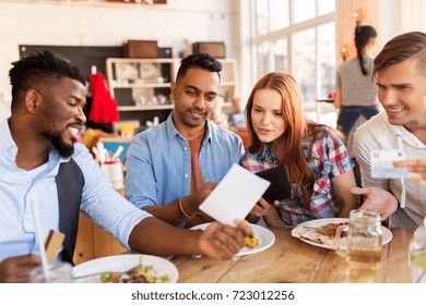 Leisure, Payment And People Concept - Happy Friends With Money And Credit Card Paying Bill For Food At Restaurant