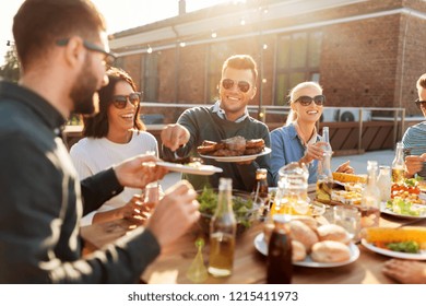 leisure and people concept - happy friends eating and drinking at barbecue party on rooftop in summer - Powered by Shutterstock