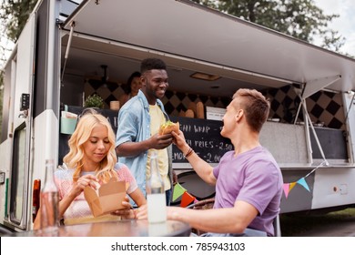 Leisure And People Concept - Happy Friends With Drinks Eating At Food Truck