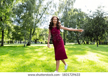 leisure and people concept - happy smiling beautiful woman with long wavy hair walking along summer park