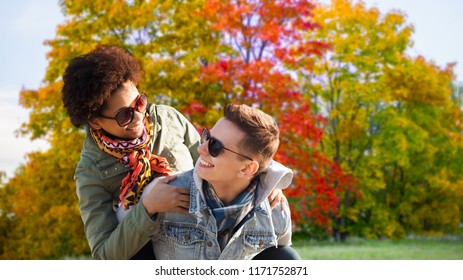 Leisure, People And Season Concept - Happy Mixed Race Teenage Couple Having Fun Over Autumn Park Background