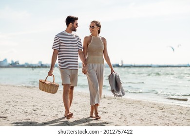 leisure, relationships and people concept - happy couple with picnic basket and blanket walking along beach - Powered by Shutterstock