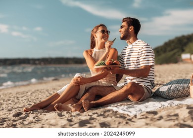 leisure, relationships and people concept - happy couple with food eating and having picnic on beach - Powered by Shutterstock