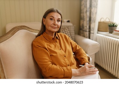 Leisure, Rest, Hobby And Retirement Concept. Portrait Of Attractive Serious Elderly Housewife With Gray Hair Sitting At Home, Making List Of Groceries Before Shopping Or Writing Down Her Thoughts