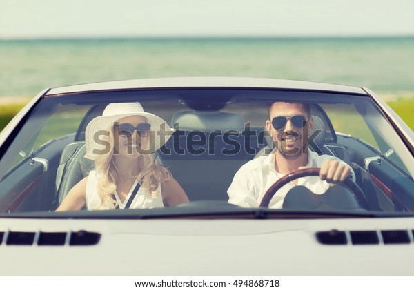 leisure, road trip,
dating, couple and people concept - happy man and woman driving in
cabriolet car outdoors