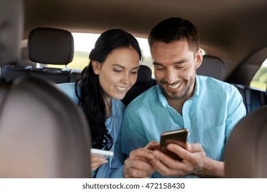 leisure, road trip, travel, technology and people concept - happy man and woman with smartphones driving in car