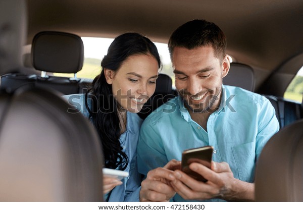 leisure, road trip,\
travel, technology and people concept - happy man and woman with\
smartphones driving in\
car