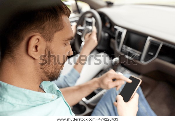 leisure, road trip,
travel, technology and people concept - happy man and woman with
smartphones driving in
car